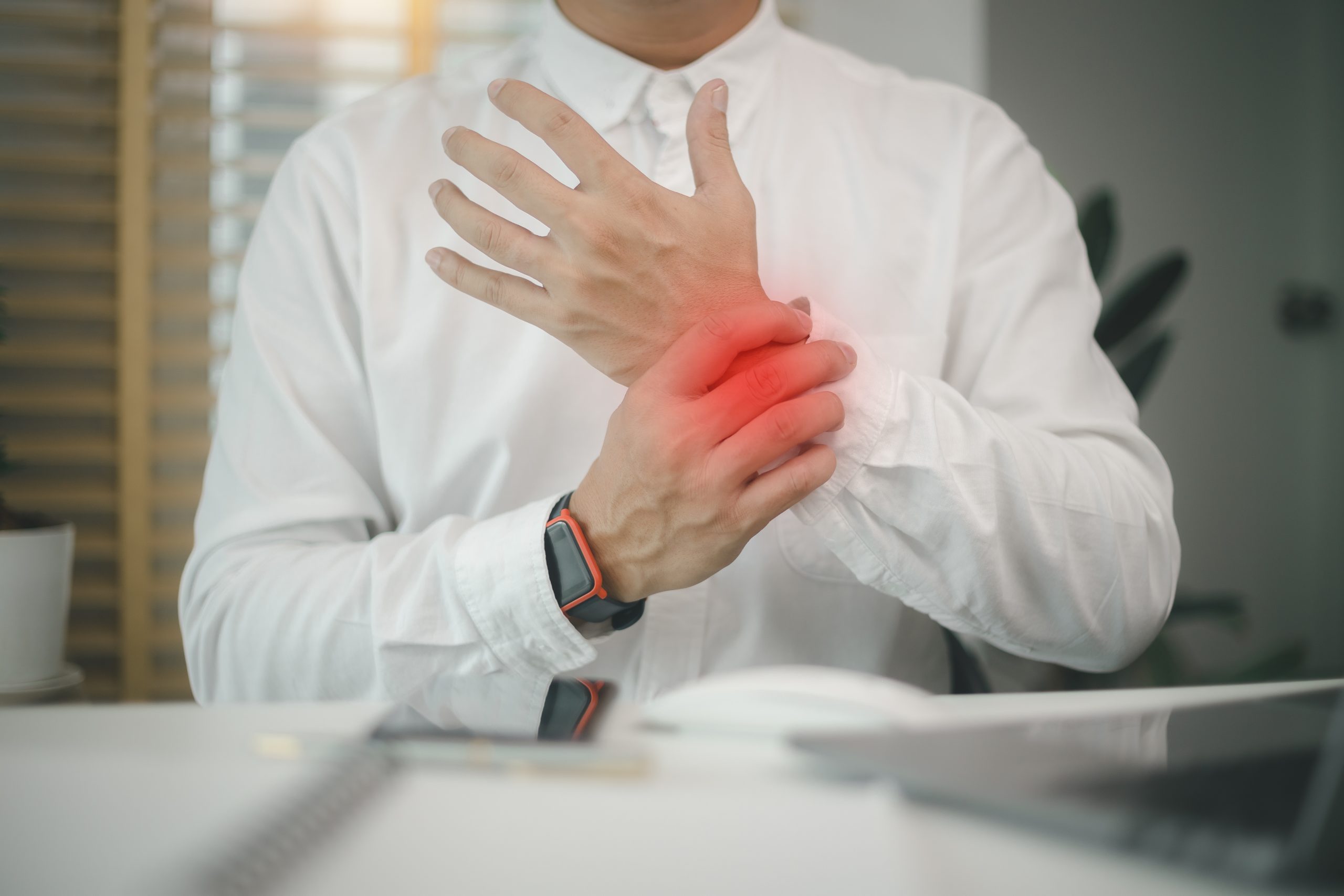 Male employee sitting office workplace with laptop, massaging sore wrist, suffering pinched nerve, stiff muscles, carpal tunnel syndrome after typing on laptop